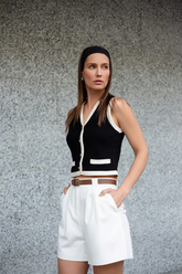 a lady wears a black knitted vest with white shorts